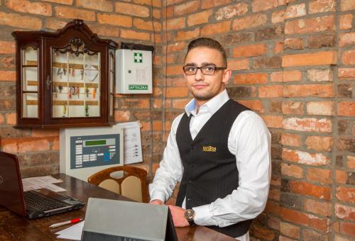 a man standing in front of a table with a laptop at Hotel Bastion in Kostrzyn nad Odrą