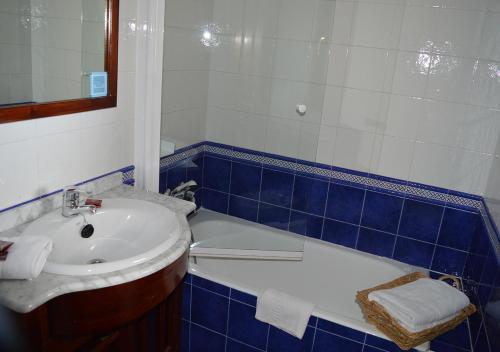 a blue and white bathroom with a sink and a tub at Posada El Valle - Adults Only in Suances