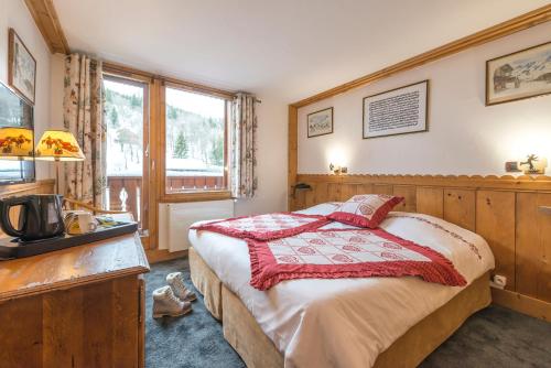a bedroom with a bed and a tv and a window at Hotel Eterlou in Méribel