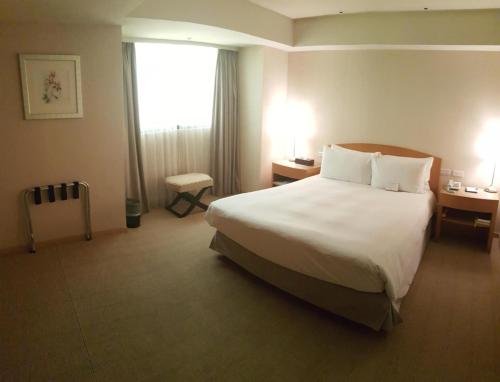 a hotel room with a large bed and a window at Chiayi Maison de Chine Hotel in Chiayi City