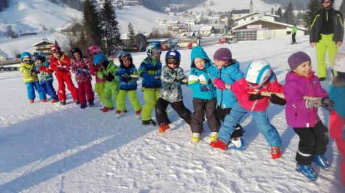 a group of children are lined up in the snow at Apartmenthaus Vergissmeinnicht in Abtenau