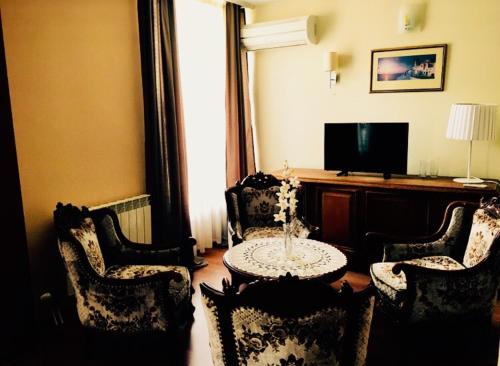 uma sala de estar com uma mesa e cadeiras e uma televisão em Hotel Shterev Karlovo em Karlovo