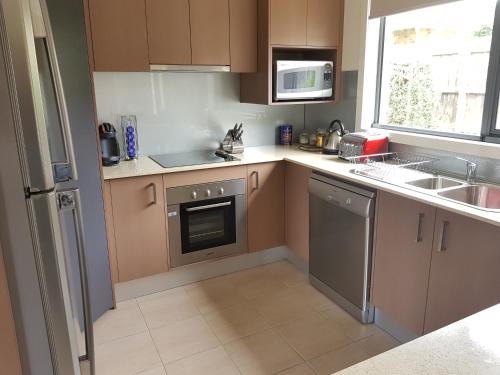 a kitchen with brown cabinets and a sink and a dishwasher at Wyndham Luxury - Free Wifi and Netflix in Cowes