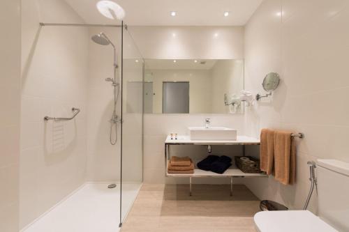een witte badkamer met een douche en een wastafel bij HC Luxe in Vecindario