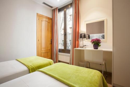 a room with two beds and a desk and a window at Bcngotic in Barcelona