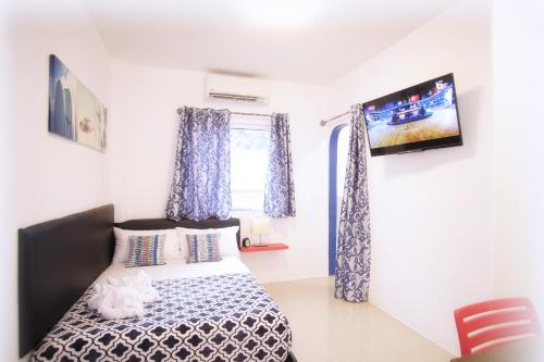 a bedroom with a bed and a tv on the wall at D´Gecko Hotel in Moalboal