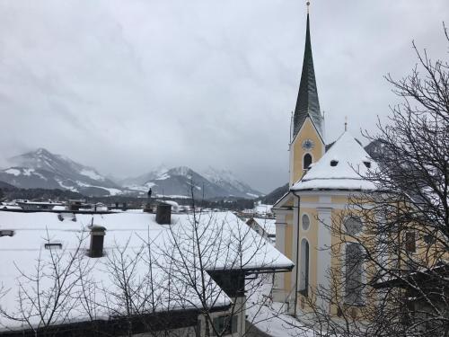 a church with a steeple with snow on the ground at Kössen DORF41 TOP2 in Kössen