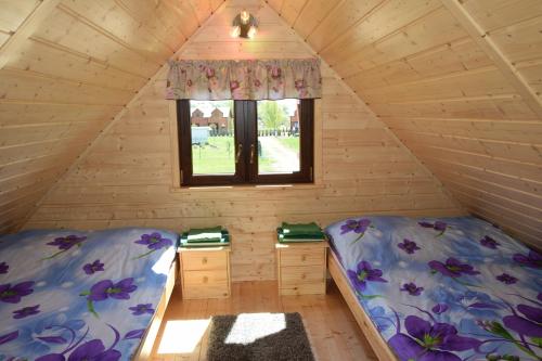 two beds in a room with a window at Ow Bursztynek in Rusinowo
