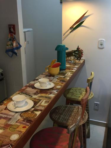 a table with chairs and plates and bowls on it at Apartamento 05 Vivendas do Serrano - Lençóis in Lençóis
