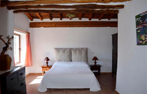 サン・リョレンツ・デ・バラフィアにあるCan Pereの白いベッドと木製の天井が備わるベッドルーム1室が備わります。