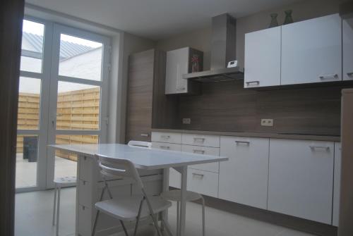 a kitchen with white cabinets and a table and chairs at De Reep in Geraardsbergen