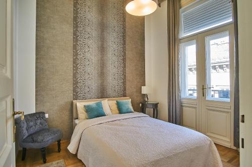 a bedroom with a bed and a chair and a window at Basilica Royal Apartment | Budapest in Budapest