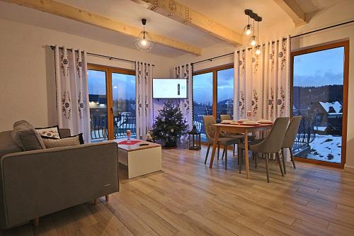 a living room with a table and a dining room at Osada domków Baca in Poronin