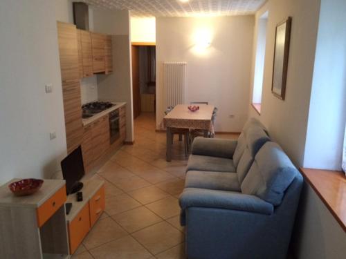 a living room with a blue couch and a kitchen at Palazzina Rosa in Spormaggiore