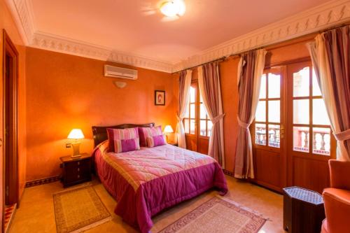a bedroom with a bed with purple sheets and windows at Villa Zahra Palmeraie in Marrakesh