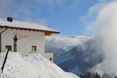 a snow covered building with a view of a mountain at Bergbauernhof Kinderparadies Oberhasenberghof in Taxenbach