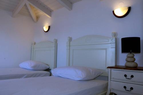 a bedroom with two beds and a tv on a dresser at Grand Bleu Apartments & Villas in Ermioni