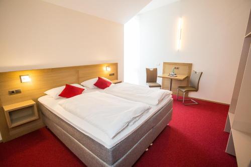 ein Schlafzimmer mit einem großen weißen Bett mit zwei roten Kissen in der Unterkunft Weingut Blank in Homburg