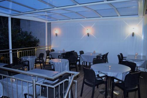 un restaurante con mesas blancas y sillas en un balcón en Hotel Locanda, en Basilea