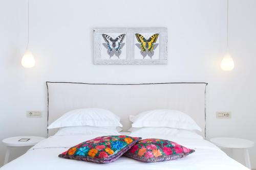 a white bed with two pillows and two butterflies on it at Myconian Villa Collection - Preferred Hotels & Resorts in Elia Beach