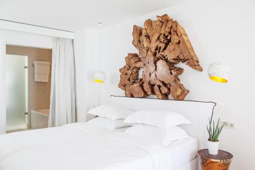 a bedroom with a bed with white sheets and a sculpture on the wall at Myconian Villa Collection - Preferred Hotels & Resorts in Elia Beach