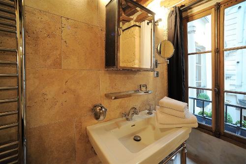 une salle de bain avec un lavabo, un miroir et une fenêtre dans l'établissement Beautiful apartment in historical Marais, à Paris