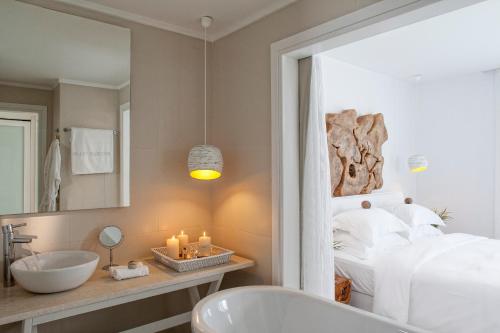 a bathroom with a bed and a sink and a mirror at Myconian Villa Collection - Preferred Hotels & Resorts in Elia Beach