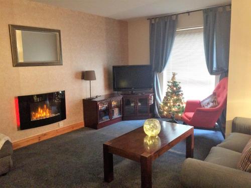 a living room with a fireplace and a christmas tree at Dunroamin Self-Catering Apartment in Aviemore