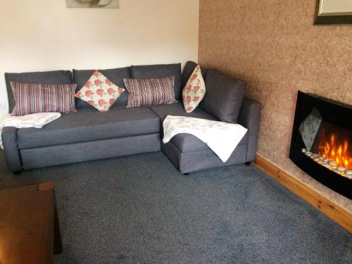 a living room with a couch and a fireplace at Dunroamin Self-Catering Apartment in Aviemore