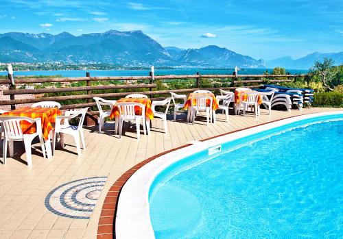 a patio with tables and chairs and a swimming pool at Residence Bellavista in Manerba del Garda