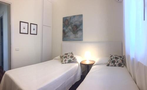 ガルダにあるWelcome Traveller ALLOGGIO TINTORETTOのベッド2台とランプが備わる部屋