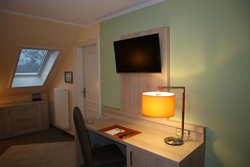 a room with a desk with a lamp and a television at Hus op de Diek in Sankt Peter-Ording