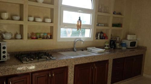 a kitchen with a sink and a stove and a window at domaine club Evasion in Tamellalt