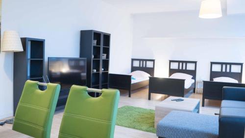 a living room with green chairs and a tv at Work & stay Langenfeld in Langenfeld