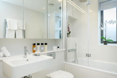 a bathroom with a sink and a toilet and a shower at Urban Chic - Basing Street in London