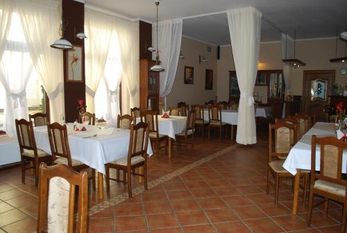 a restaurant with white tables and chairs and white curtains at Hotel Anka in Słubice