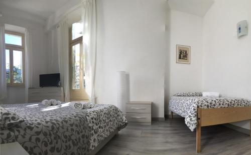 a white bedroom with two beds and a television at Hotel Firenze Lugano in Lugano