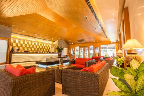 a living room with brown wicker furniture and orange pillows at Novotel Rayong Rim Pae Resort in Klaeng