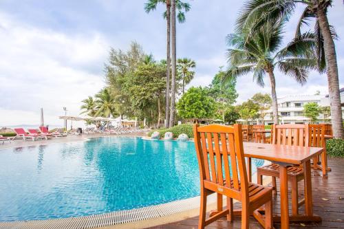a table and chairs next to a swimming pool at Novotel Rayong Rim Pae Resort in Klaeng