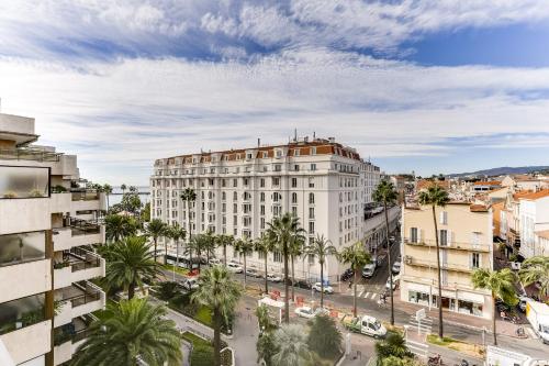 un edificio de apartamentos en una ciudad con palmeras en Agence AICI - Appartements Gray d'Albion, en Cannes