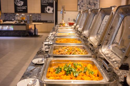 a row of trays of food on a buffet line at Novotel Rayong Rim Pae Resort in Klaeng