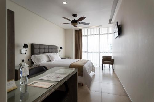 1 dormitorio con 1 cama y escritorio con ventilador de techo en Hotel Maria Fernanda Inn, en Zitácuaro