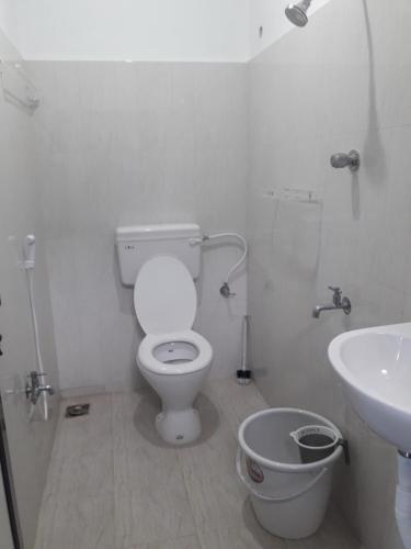 a white bathroom with a toilet and a sink at Squirrel Nest Guest House in Mahabalipuram