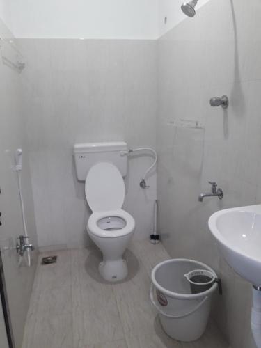 a white bathroom with a toilet and a sink at Squirrel Nest Guest House in Mahabalipuram