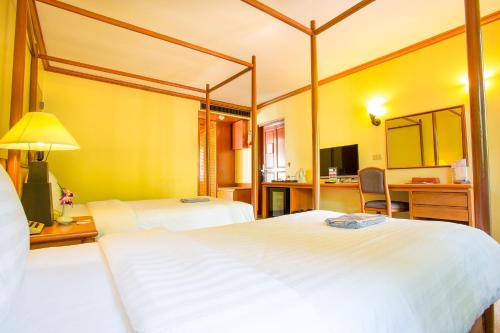 a hotel room with two beds and a desk at Novotel Rayong Rim Pae Resort in Klaeng