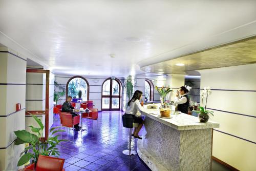 a lobby with people sitting at a counter in a restaurant at Lloyd's Baia Hotel in Vietri sul Mare