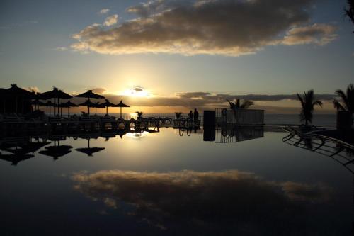 a swimming pool with the sunset in the background at VIK Hotel San Antonio in Puerto del Carmen
