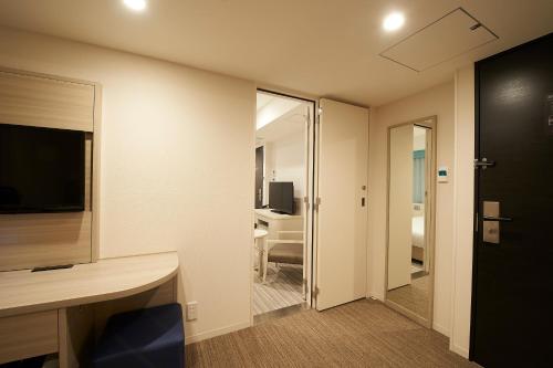 a room with a desk and a room with a television at Sotetsu Fresa Inn Ginza Sanchome in Tokyo