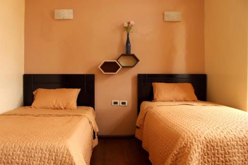 two beds in a room with orange walls at Hotel Norte in Cuenca
