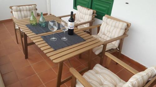 drewniany stół z 2 butelkami i 2 kieliszkami wina w obiekcie Apartamentos Casa Cipri w mieście Playa Blanca